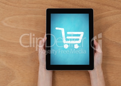 Part of hands holding a digital tablet against wooden background