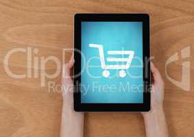 Part of hands holding a digital tablet against wooden background