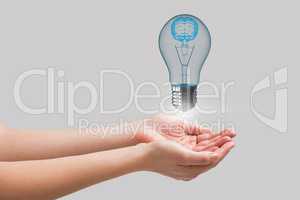 Light bulb floating above hands with grey background