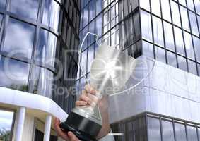 business hand with trophy with flare, in front of business building
