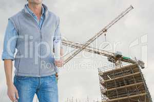 Architect standing on holds plan against building under construction background