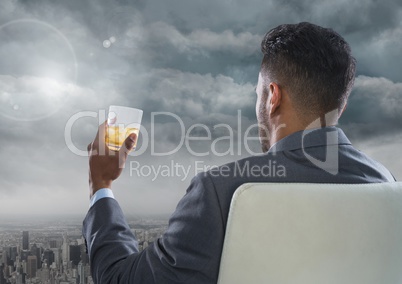 Businessman Back Sitting in Chair with drinks glass and dark clouds over city