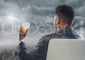 Businessman Back Sitting in Chair with drinks glass and dark clouds over city