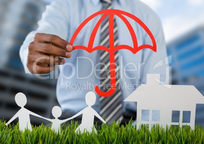 Holding umbrella over insurance cut outs home family with buildings