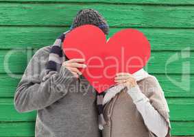 couple behind the heart with green wood background