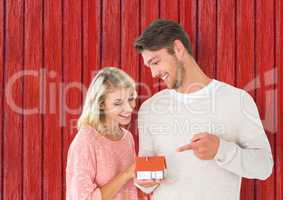 couple with little house in the hands with red wood background
