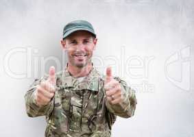 soldier thumbs up and smiling. concrete wall