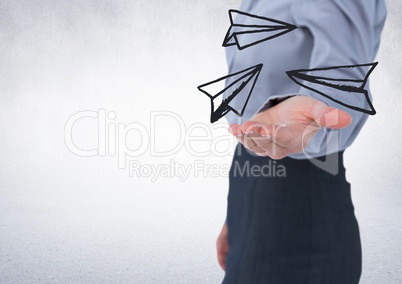 Business woman mid section with white paper airplane doodle in hand against white wall