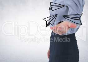Business woman mid section with white paper airplane doodle in hand against white wall