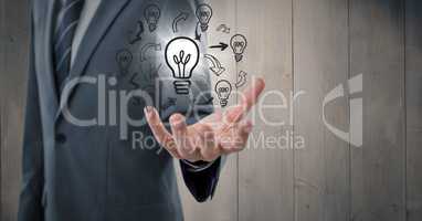 Business man mid section with lightbulb doodles and flare against grey wood panel