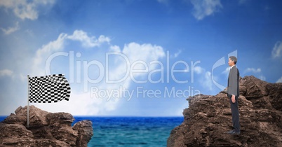 Digital composite image of businessman standing on rock looking at checkered flag standing against s