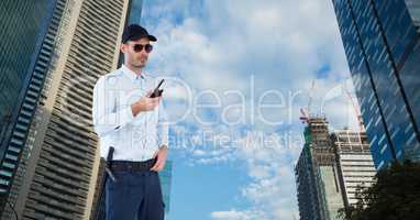 Security guard holding walkie talkie while standing against buildings