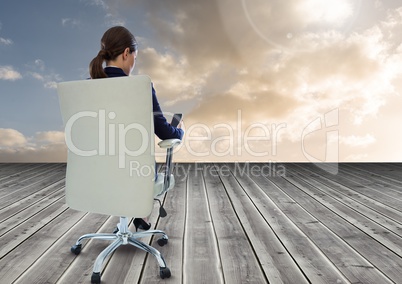 Businesswoman Back Sitting in Chair with mobile phone on wood with cloudy sky