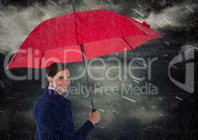 Business woman looking over shoulder with umbrella against rainy sky