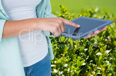Model is touching tablet computer screen against plant background
