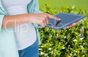 Model is touching tablet computer screen against plant background