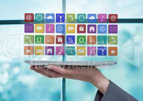 Businesswoman holding tablet with apps icons by window