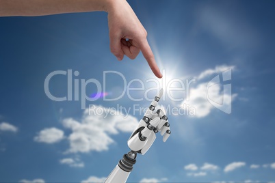 human hand is touching robot hand against sky background