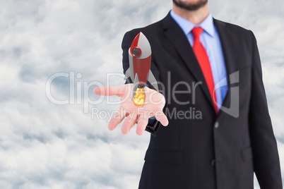 Businessman is holding a rocket taking off from his hand against sky background