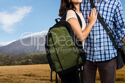 travelers carrying bag, arm in arm, against mountain landscape background