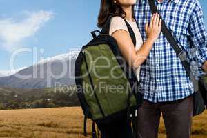 travelers carrying bag, arm in arm, against mountain landscape background