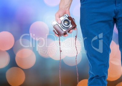 Hand holding camera with sparkling light bokeh background