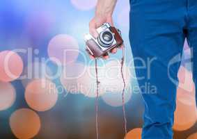 Hand holding camera with sparkling light bokeh background