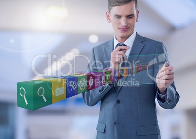 Businessman holding glass screen with apps  in large bright space