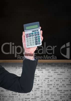 Hand with calculator against black chalkboard with white brick wall