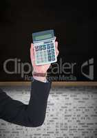 Hand with calculator against black chalkboard with white brick wall