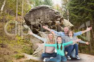 Family is happy to pose for souvenir photo in front of rock against forest background