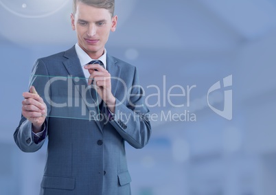 Businessman holding glass screen in large blue space