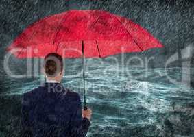 Back of business woman with umbrella in rain against stormy sea