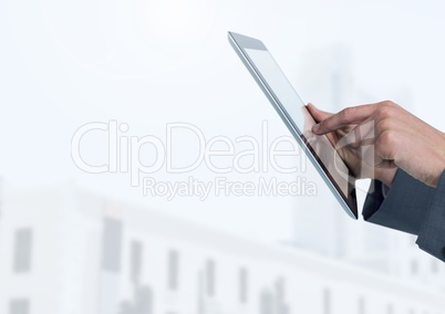 Businessman holding tablet in front of bright buildings