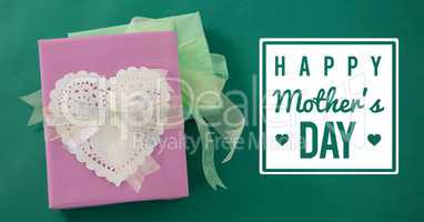 Pink gift with a white heart for mother's day on green background