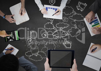 Overhead of people writing on grey surface with white cloud doodles