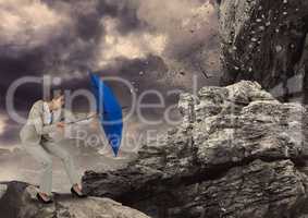 Digital image of rocks falling on businesswoman with blue umbrella standing against sky
