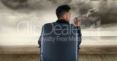 Rear view of businessman smoking cigar while sitting on chair