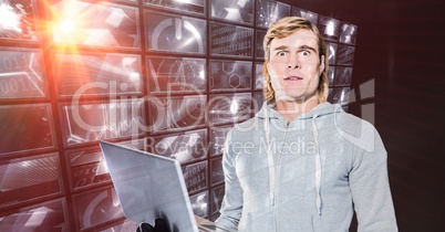 Hacker holding laptop standing by digital screen