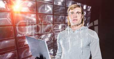 Hacker holding laptop standing by digital screen