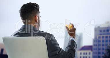 Back of seated business man drinking and looking at blurry buildings