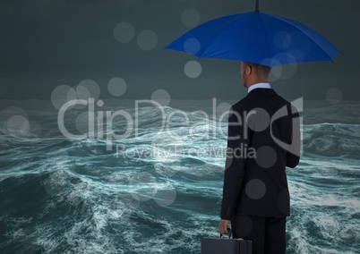 Back of business man with umbrella against stormy sea with bokeh