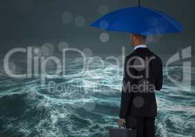 Back of business man with umbrella against stormy sea with bokeh