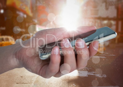 Hand with phone against blurry street with bokeh and flares