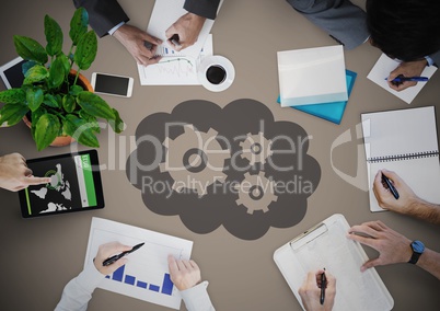 Overhead of people writing with grey cloud and gear graphic against brown background