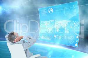 Side view of businessman sitting on a chair looking at graphics on world wide map