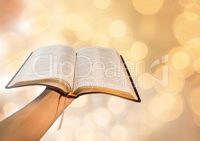 Hand holding book with sparkling light bokeh background