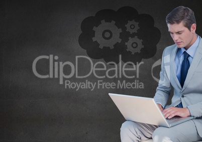 Business man with laptop against grey wall and cloud with gear graphic Business man with laptop against grey wall and cloud with gear graphic