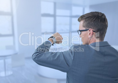 Businessman holding arm with watch to eyes in blue office