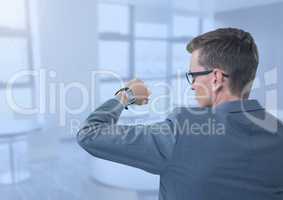 Businessman holding arm with watch to eyes in blue office